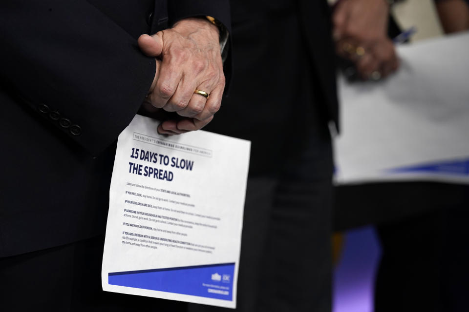 Vice President Mike Pence holds a information sheet during a press briefing with the coronavirus task force, in the Brady press briefing room at the White House, Monday, March 16, 2020, in Washington. (AP Photo/Evan Vucci)