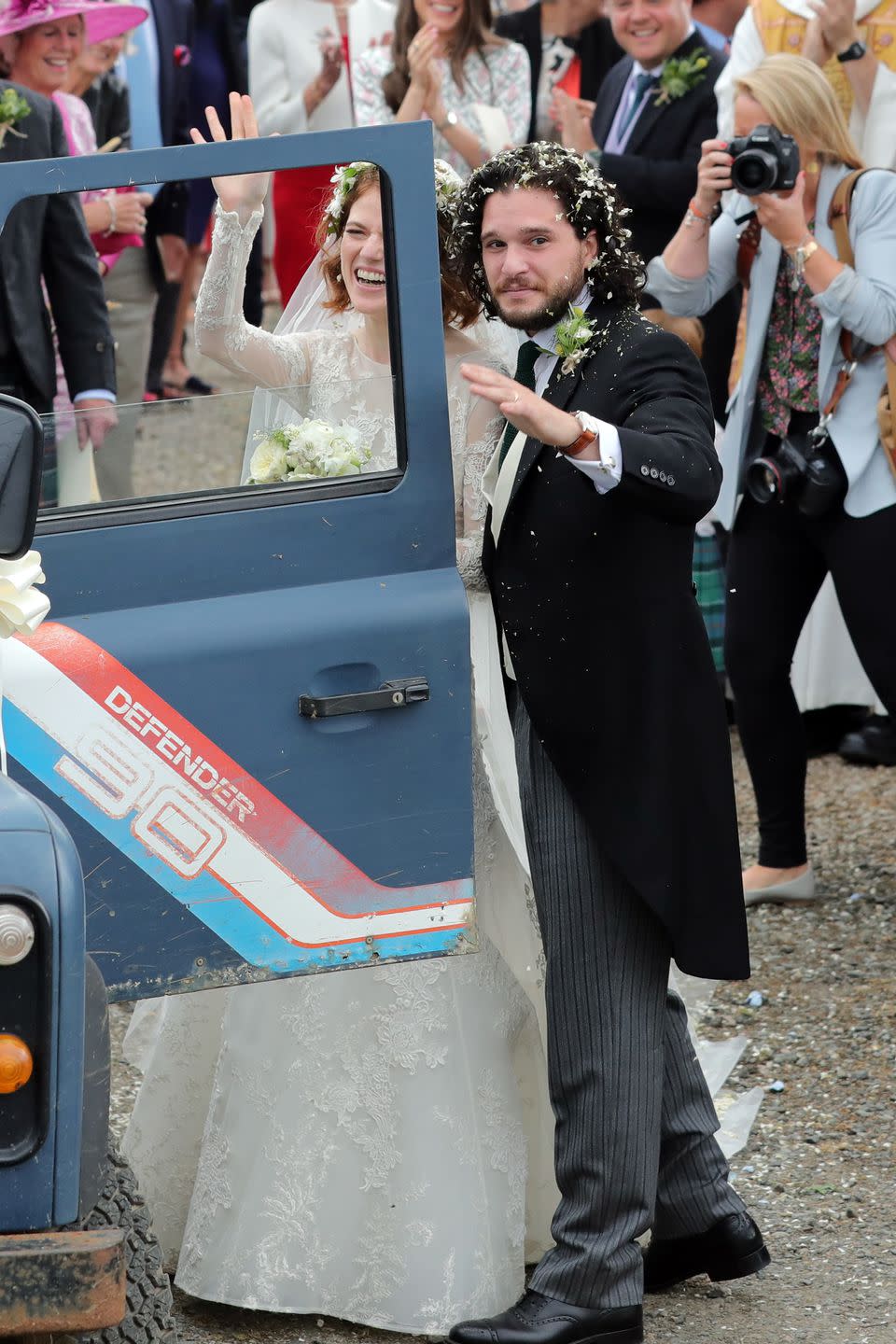<p>The bride and groom wave to the photographers before departing.</p>