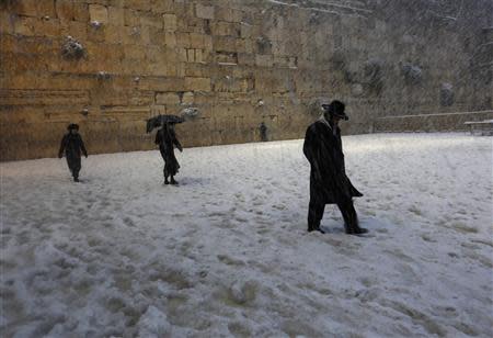 Ultra-Orthodox Jews walk near the Western Wall in Jerusalem's Old City during a snowstorm December 13, 2013. REUTERS/Darren Whiteside
