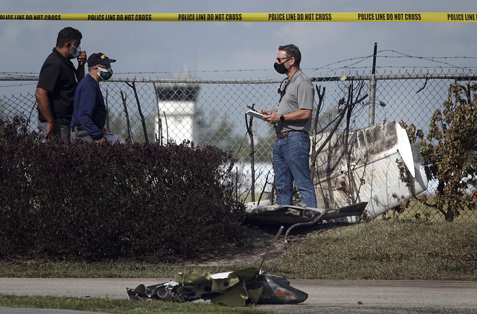 NTSB investigators work the scene of a plane crash near North Perry Airport in Pembroke Pines, Fla. Tuesday, March 16, 2021. A four-year-old child riding in a vehicle on the ground and the pilot and passenger in the plane were killed. (Joe Cavaretta/South Florida Sun-Sentinel via AP)