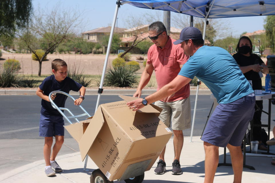 Dylan Pfeifer uses a lift to move a box filled with donated canned and boxed foods to his home in Chandler, Ariz., Saturday, April 3, 2021, to safely store the items until they are given to St. Mary's Food Bank. Pfeifer hosted his third food drive since October in response to the coronavirus pandemic. He collected about $450. (AP Photo/Cheyanne Mumphrey)