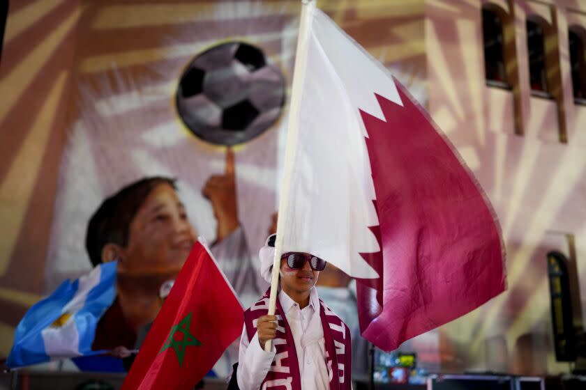 A child holds a flag from Qatar at Katara Cultural Village in Doha, Qatar, Sunday, Dec. 11, 2022. (AP Photo/Natacha Pisarenko)