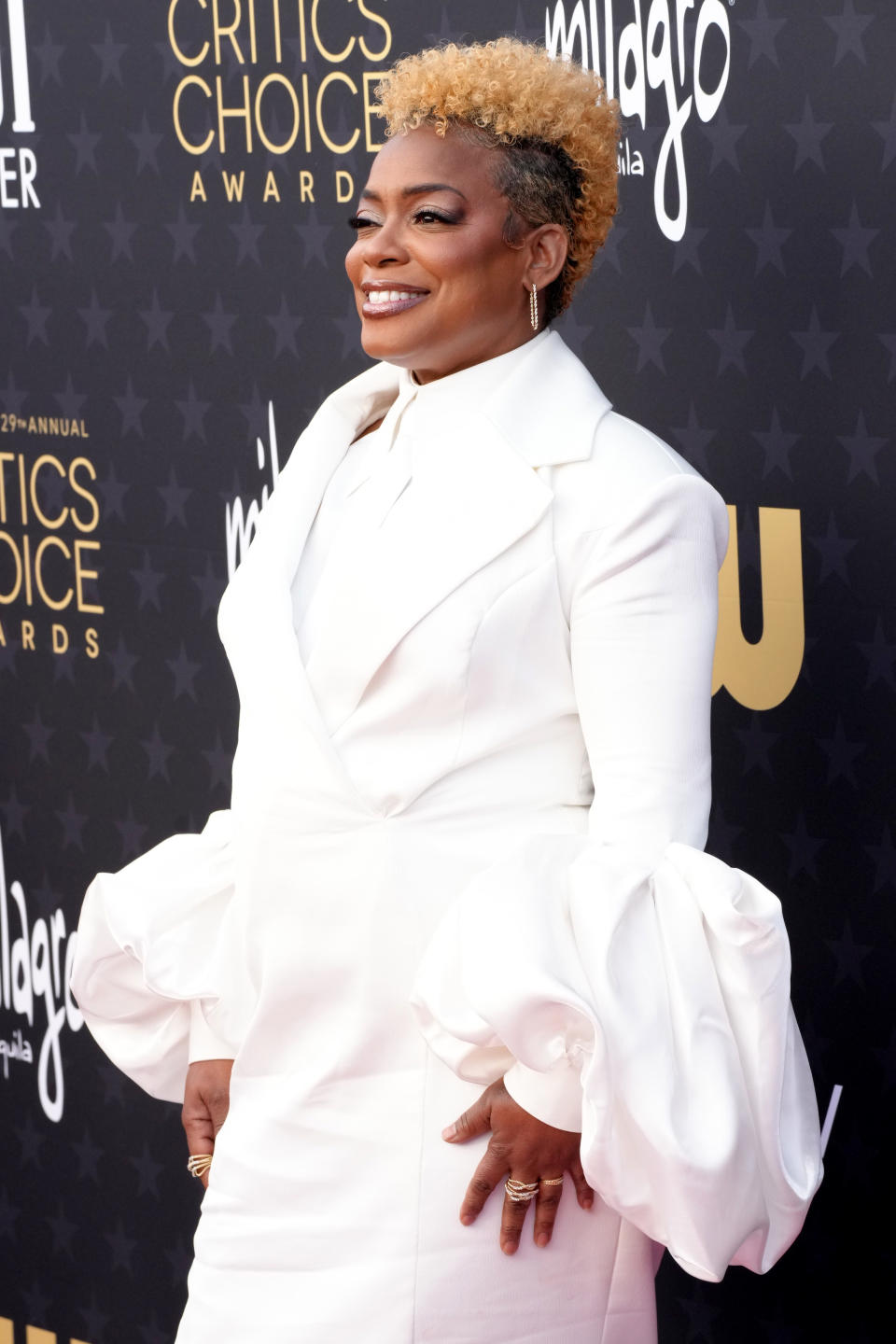 Aunjanue Ellis-Taylor in a suit with large ruffle detail posing in front of the Critics' Choice Award backdrop