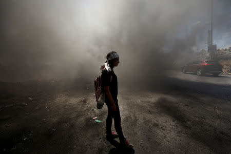 A Palestinian girl stands amongst smoke during clashes with Israeli troops at a protest near the Jewish settlement of Beit El, near Ramallah, in the occupied West Bank June 29, 2018. REUTERS/Mohamad Torokman