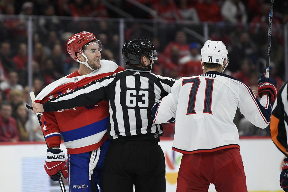 Linesman Trent Knorr (63) separates Washington Capitals right wing Tom Wilson, left, and Columbus Blue Jackets left wing Nick Foligno (71) during the second period of an NHL hockey game, Monday, Dec. 9, 2019, in Washington. (AP Photo/Nick Wass)