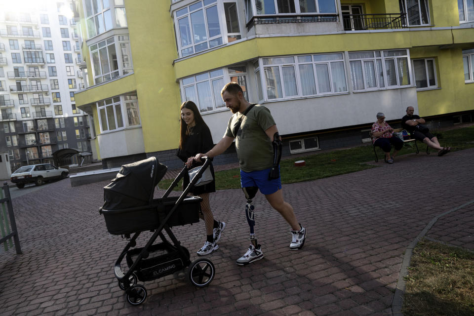 Mykhailo Yurchuk, former Ukrainian paratrooper of 95th brigade and his wife Maria pushes a pushchair with their newborn daughter Olivia near their house in Lviv, Ukraine, Wednesday, Aug. 23, 2023. He was injured on March 15, 2022, in the first days of the full-scale invasion when a tank shell exploded as he was pulling comrades from a burning armored personnel carrier. Ukraine is facing the prospect of a future with upwards of 20,000 amputees, many of them soldiers who are also suffering psychological trauma from their time at the front. (AP Photo/Evgeniy Maloletka)