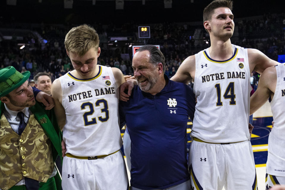 Notre Dame coach Mike Brey sings the alma mater with the Notre Dame Leprechaun, Dane Goodwin (23), and Nate Laszewski (14) after the team's win over Pittsburgh inan NCAA college basketball game Wednesday, March 1, 2023, in South Bend, Ind. (AP Photo/Michael Caterina)