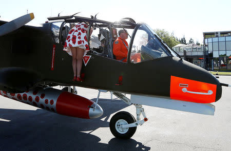 A hostess of the Bronco demo team helps a passenger in an OV-10 Bronco aircraft, decorated with World War One commemoration motifs, at Flanders international airport, ahead of the world's first Short Take Off & Landing competition on sand, in Wevelgem, Belgium May 8, 2018. REUTERS/Francois Lenoir