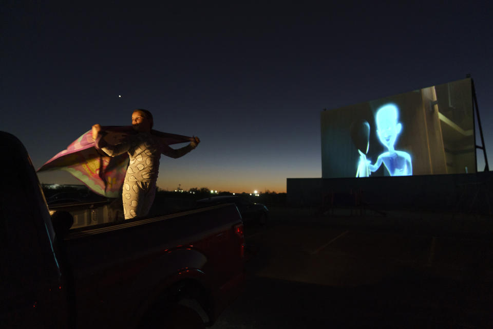 Raylee Bothwell, 8, holds up her Minnie Mouse blanket in the wind while watching her first drive-in movie from the back of her family’s pickup truck in Midland, Texas., Tuesday, Oct. 12, 2021. Centered around the boomtowns of Midland and Odessa, the Permian is now the top oil and gas producing region in the United States, which in turn is the world’s No. 1 producer. (AP Photo/David Goldman)