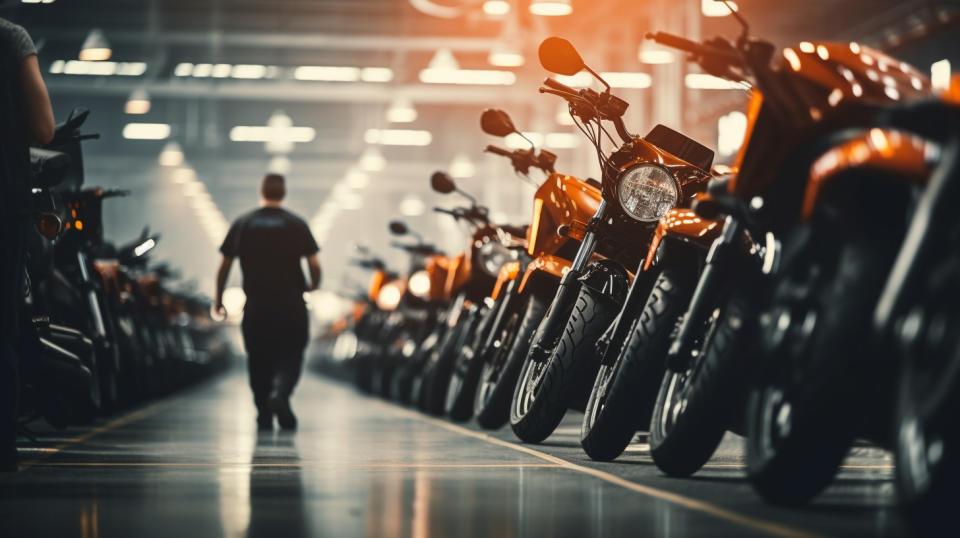 A fleet of motorcycles and vehicles lined up in an assembly line with workers in the background.