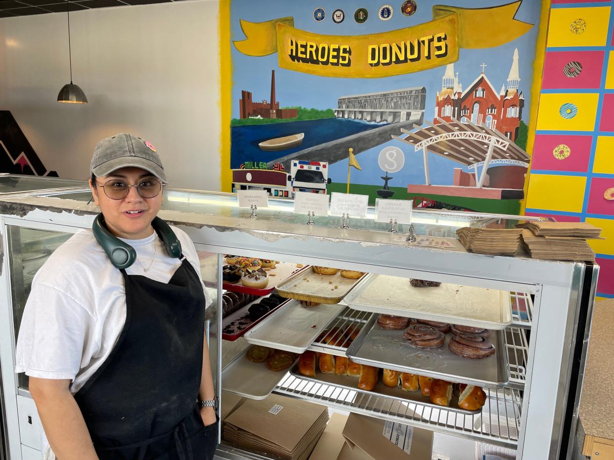 Jocelyn Sao, co-owner of Heroes Donuts on Washington Road in Augusta, pauses behind the bakery counter as a locally-inspired mural covers part of a wall in the background. The bakery announced its last day open to customers would be Nov. 25.