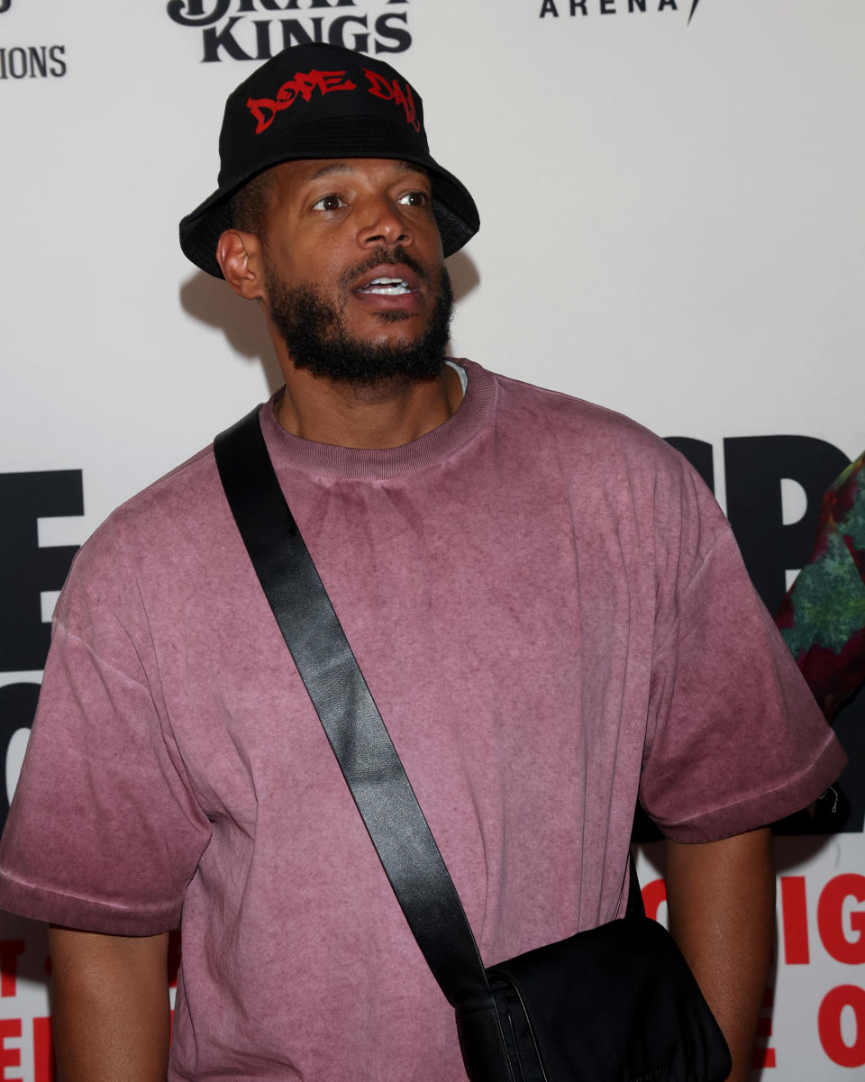 Marlon Wayans at T-Mobile Arena, wearing a pink shirt and Black and red bucket hat.