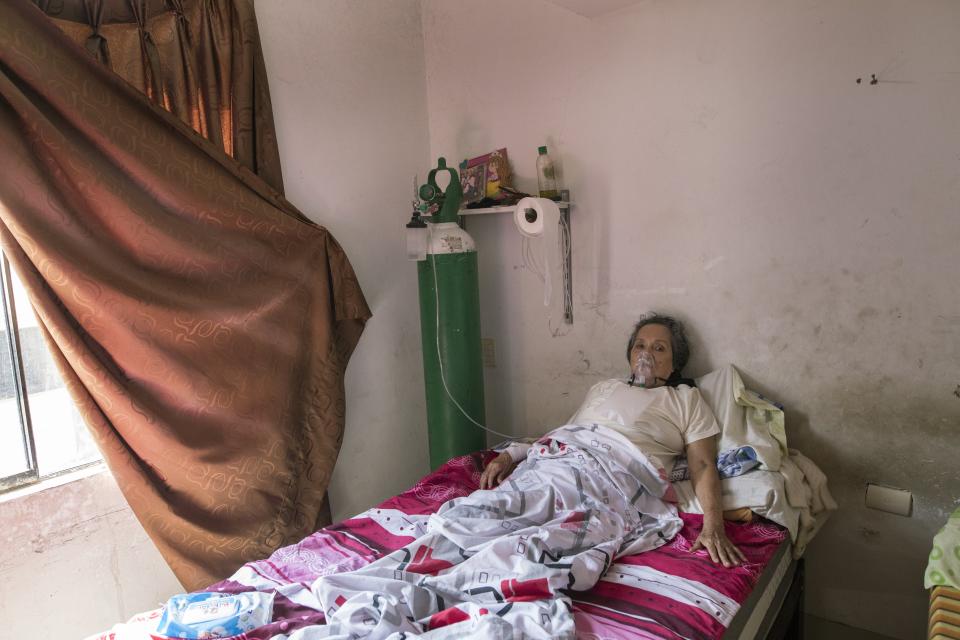 Clara Reina Villacorta, 74, who is infected with the COVID-19 virus, breathes in oxygen inside her home in the Villa El Salvador neighborhood of Lima, Peru, Tuesday, April 6, 2021, amid the new coronavirus pandemic. (AP Photo/Rodrigo Abd)