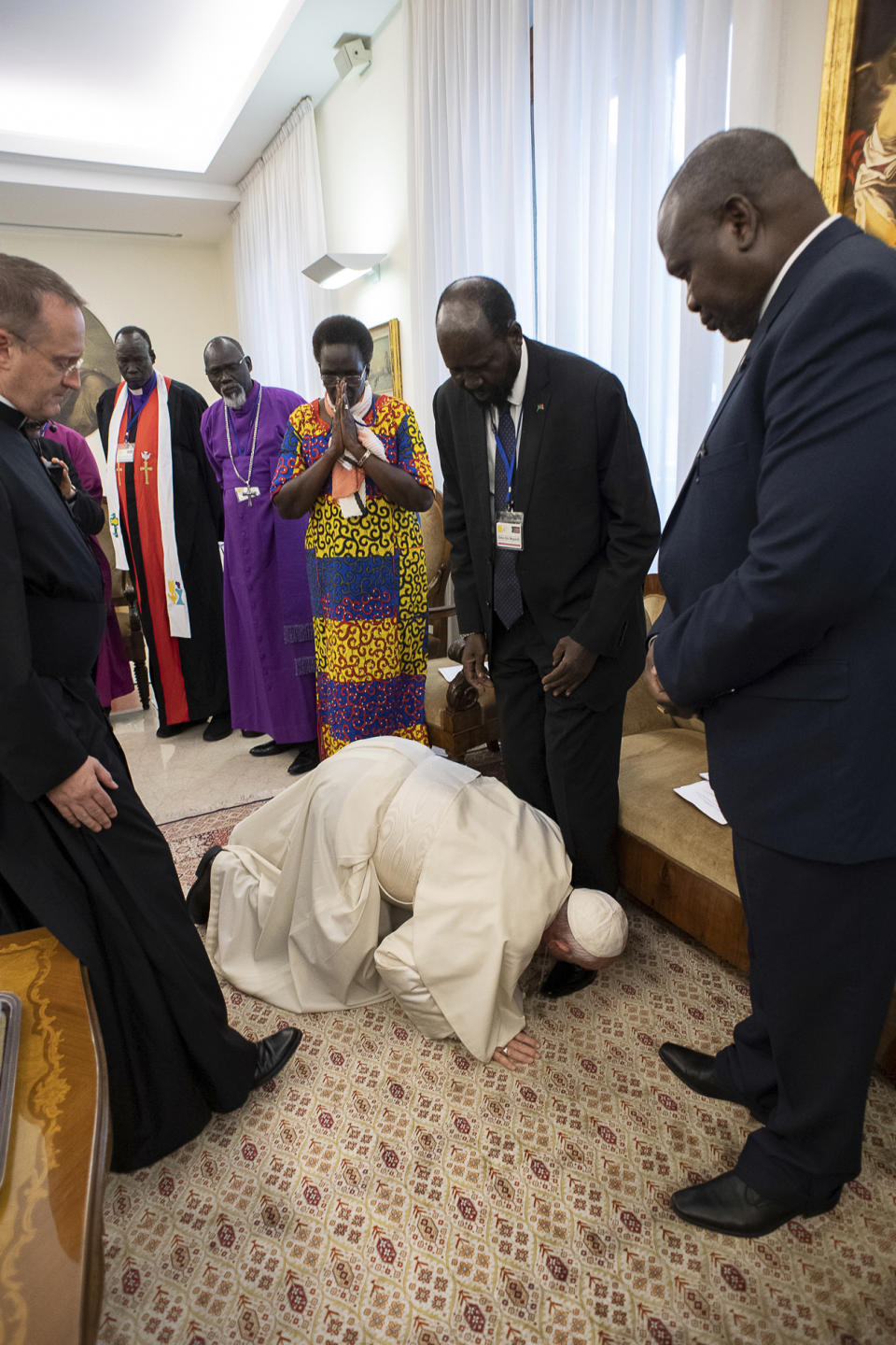 Pope Francis kneels to kiss the feet of South Sudan's President Salva Kiir Mayardit, at the Vatican, Thursday, April 11, 2019. Pope Francis has closed a two-day retreat with South Sudan authorities at the Vatican with an unprecedented act of respect, kneeling down and kissing the feet of the African leaders. (Vatican Media via AP)