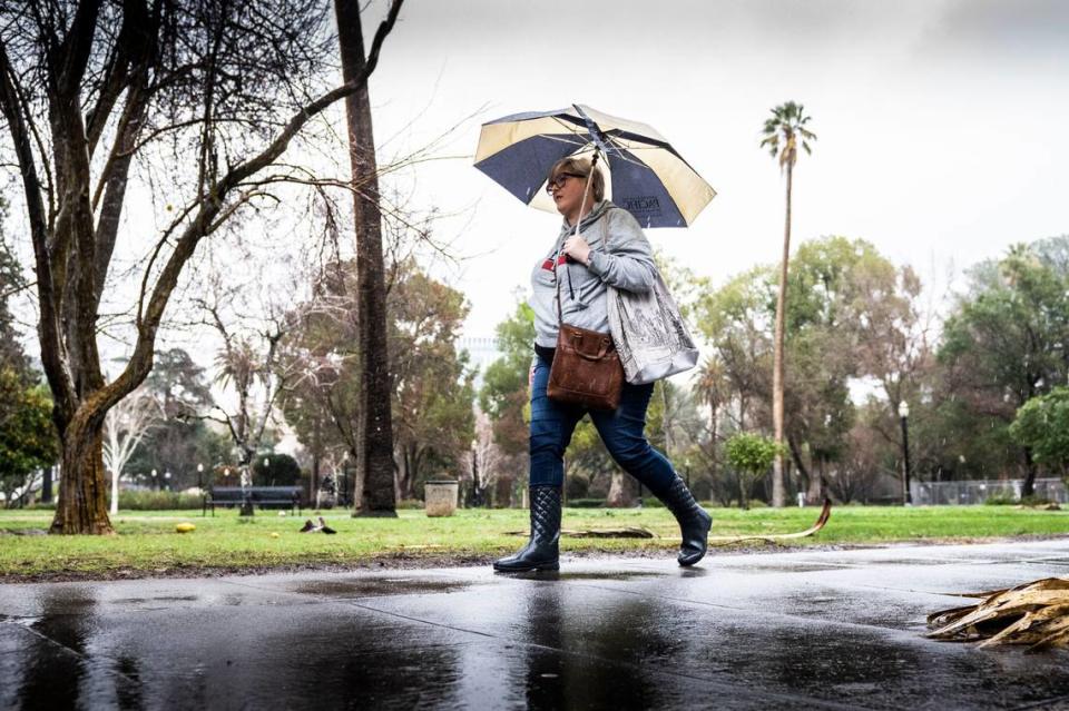 Andrea Clayton of Sacramento walks to her state job in the rain on N Street on Thursday, January 5, 2023.