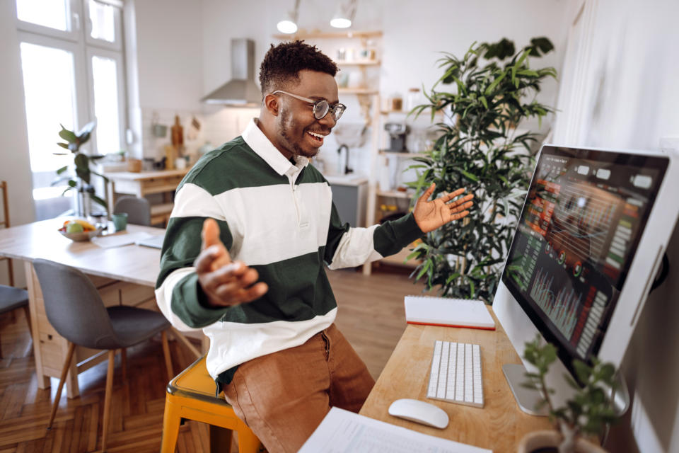 A person cheering while looking at graphs on a computer monitor