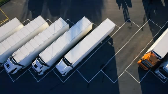 A bird's-eye view of several semi trucks parked at a rest stop.