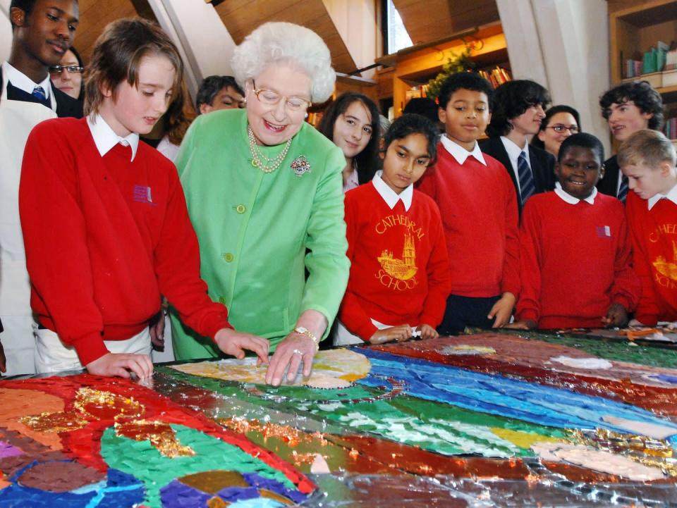 <p>The monarch gives some artistic help to a group of children, while they craft a nativity scene collage at Southwark Cathedral School.</p>