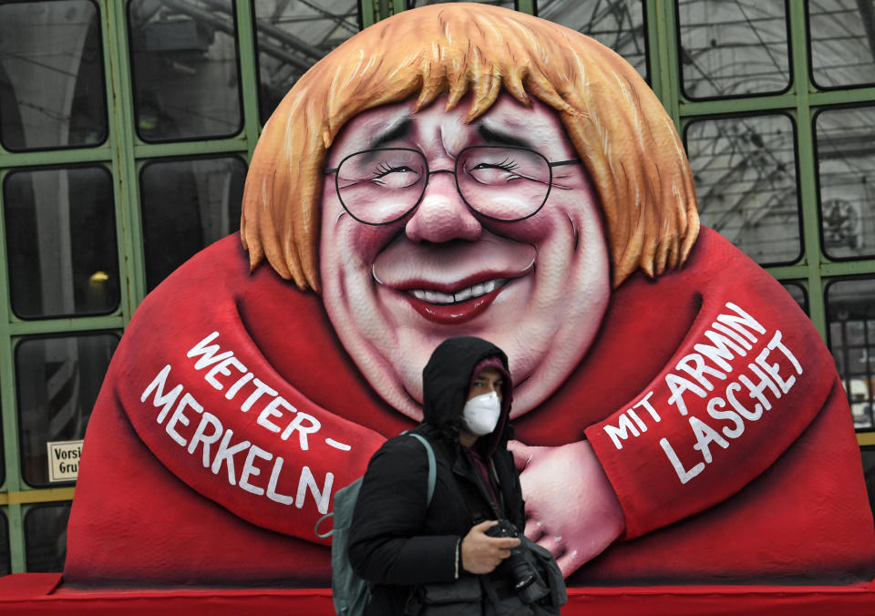A political carnival float depicting German chancellor Angela Merkel and her possible successor Governor Armin Laschet is rolled out to be shown in the streets of Duesseldorf, Germany, Monday, Feb. 15, 2021. Because of the coronavirus pandemic the traditional 'Rosenmontag' carnival parade are canceled but eight floats are pulled through the empty streets in Duesseldorf, where normally hundreds of thousands of people would celebrate the street carnival. (AP Photo/Martin Meissner)