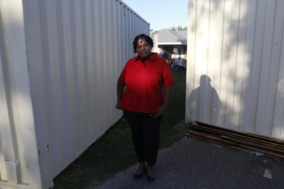 Lydia Larce stands in front of construction containers outside her home in Lake Charles, La., on Thursday, March 31, 2022. More than a year after Hurricane Laura wreaked havoc on area, Larce is living in a FEMA trailer behind her home. She fears that emissions from the oil and gas industry — including the growing number of liquid natural gas export facilities along the Gulf Coast — will worsen global warming. "Our politicians in D.C., they're not taking it seriously," she says. (AP Photo/Martha Irvine)