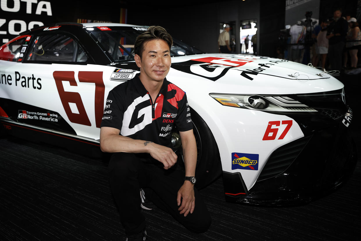 LE MANS, FRANCE - JUNE 07:  Kamui Kobayashi of Japan poses next to the #67 Toyota Camry TRD car he will drive at Indianapolis Motor Speedway later this year in a press conference ahead of the 100th anniversary of the 24 Hours of Le Mans at the Circuit de la Sarthe June 7, 2023 in Le Mans, France. (Photo by Chris Graythen/Getty Images)