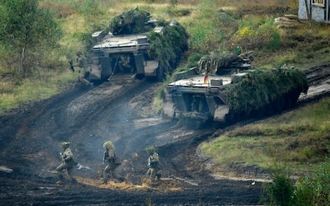 Armoured infantryman of the Bundeswehr, the German armed forces, run through mud during a simulated attack during military exercises in October  - Credit: Alexander Koerner/ Getty Images 