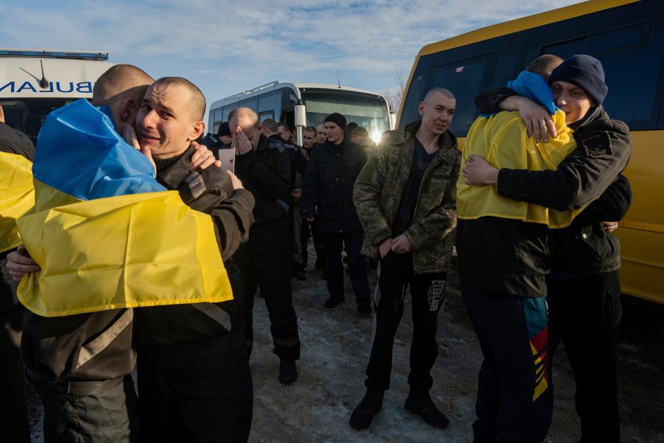 Recently swapped Ukrainian prisoners of war covered in national flags hug each other after a prisoner exchange on the Ukrainian Russian border, on Wednesday, Jan. 31, 2024.