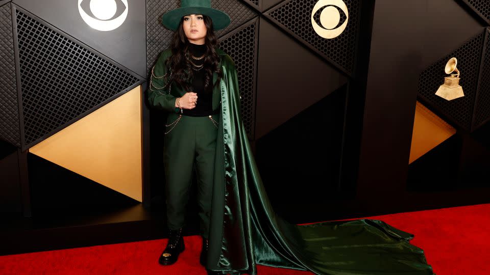 Emerging songwriter and producer Alex Ritchie gave her suit some added flair with a long flowing green cape, matching wide-brim hat and gold chains. - Frazer Harrison/Getty Images