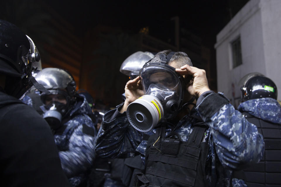 A Lebanese policeman adjusts his gas mask during clashes with supporters of Lebanon's former Prime Minister Saad Hariri, who burned tires and closed a road in Beirut, Lebanon, Friday, Dec. 20, 2019. (AP Photo/Maya Alleruzzo)