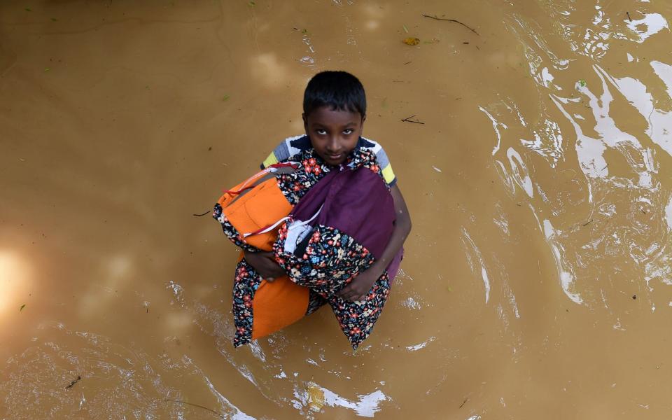 A Sri Lankan boy carries pillows through floodwaters from his home in Kelaniya - AFP