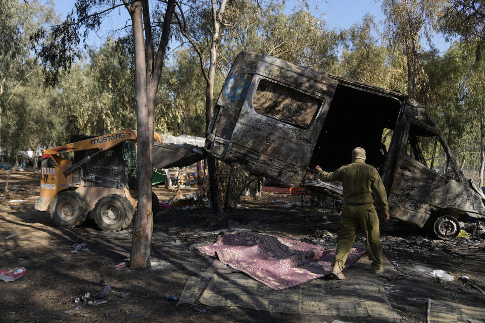 Israeli military removes a burned van from the site of a music festival near the border with the Gaza Strip in southern Israel on Thursday. Oct. 12, 2023. At least 260 Israeli festivalgoers were killed during the attack by Hamas gunmen last Saturday. (AP Photo/Ohad Zwigenberg)