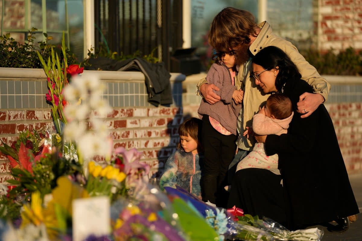 A family gathers at a memorial outside the Star Ballroom Dance Studio in Monterey Park (Copyright 2023 The Associated Press. All rights reserved)