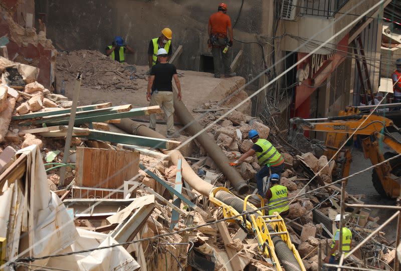 Volunteers and a member of the Chilean rescue team dig through the rubble of buildings which collapsed due to the explosion at the port area, after signs of life were detected, in Gemmayze, Beirut
