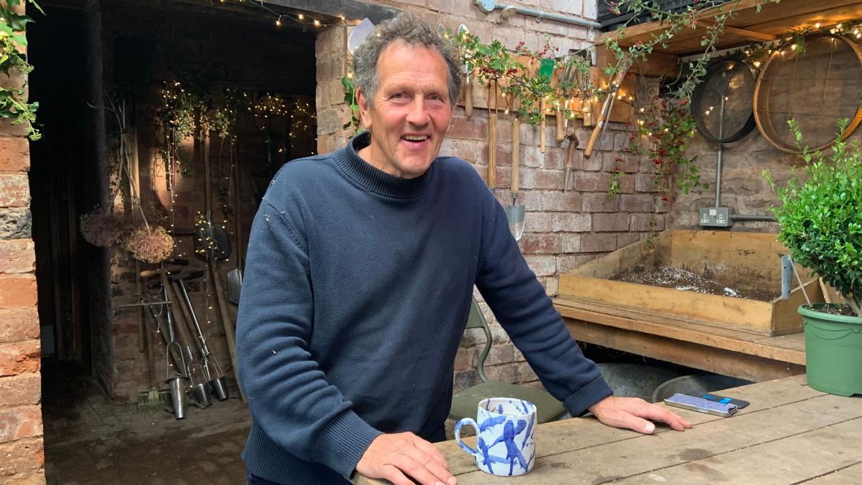  Monty Don wearing a navy jumper and drinking a cup of tea in the garden for Gardeners' World 2023. . 