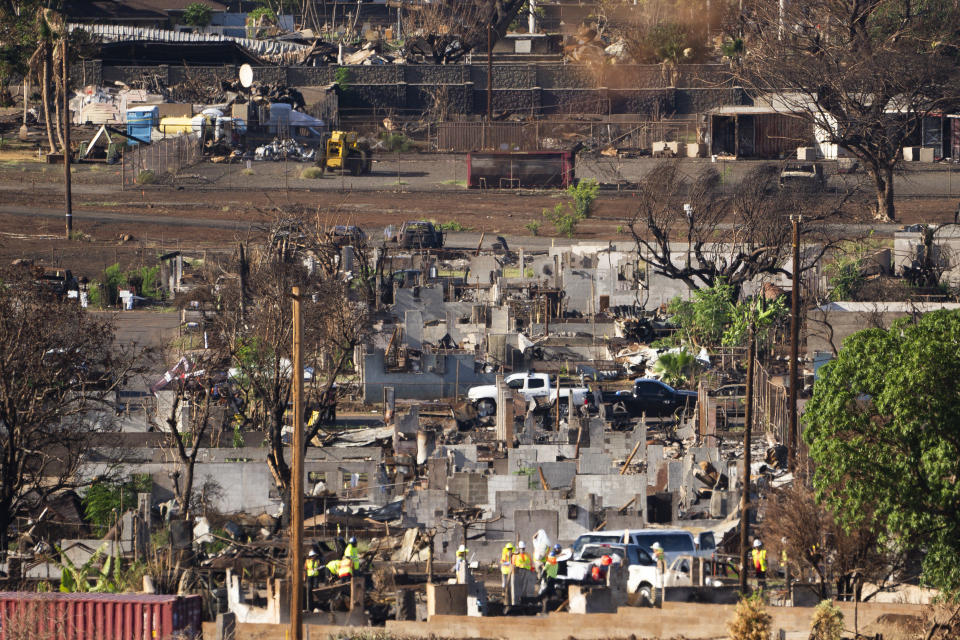 Crews work next to destroyed buildings, Wednesday, Dec. 6, 2023, in Lahaina, Hawaii. Recovery efforts continue after the August wildfire that swept through the Lahaina community on the Hawaiian island of Maui, the deadliest U.S. wildfire in more than a century. (AP Photo/Lindsey Wasson)