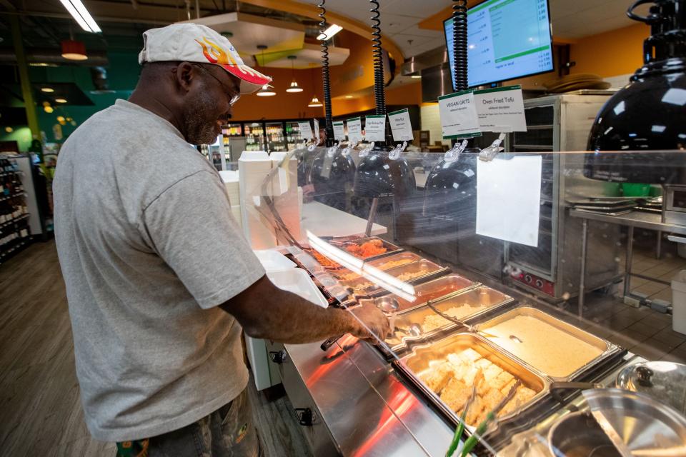 A customer fills his tray with the Friday fish special from the hot bar at Community Co-op Market on Friday, Feb. 9, 2024.