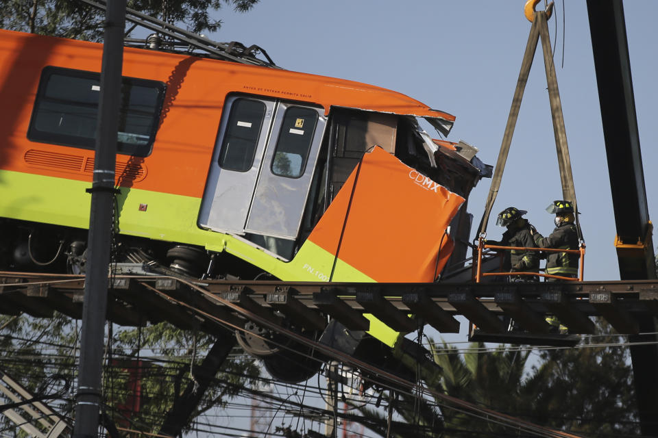 Bomberos trabajando para descolgar hasta el suelo un vagón de metro que quedó suspendido en un tramo elevado del metro, en Ciudad de México, el martes 4 de mayo de 2021. Al menos 24 personas murieron y más de 70 resultaron heridas tras el desplome de un paso elevado del metro. (AP Foto/Fernando Llano)