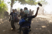 A Central American migrant throws a stone at Mexican National Guards after they crossed the Suchiate River from Guatemala to Mexico, on the riverbank near Ciudad Hidalgo, Mexico, Monday, Jan. 20, 2020. More than a thousand Central American migrants hoping to reach United States marooned in Guatemala are walking en masse across a river leading to Mexico in an attempt to convince authorities there to allow them passage through the country. (AP Photo/Santiago Billy)