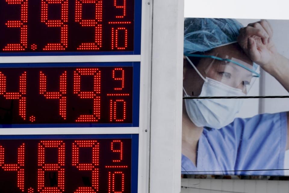 FILE - Prices are displayed on a sign at a gas station in Milwaukee on Monday, March 14, 2022, with a billboard for medical services in the background. With prices rising at their fastest rate in generations — and already lasting longer than many economists expected — the fear is that households across the country will start to see high, persistent inflation as the new normal. If that becomes the case, they could ramp up their purchases in hopes of buying ahead of further price increases, among other moves that would keep inflation elevated or push it even higher. (AP Photo/Morry Gash, File)