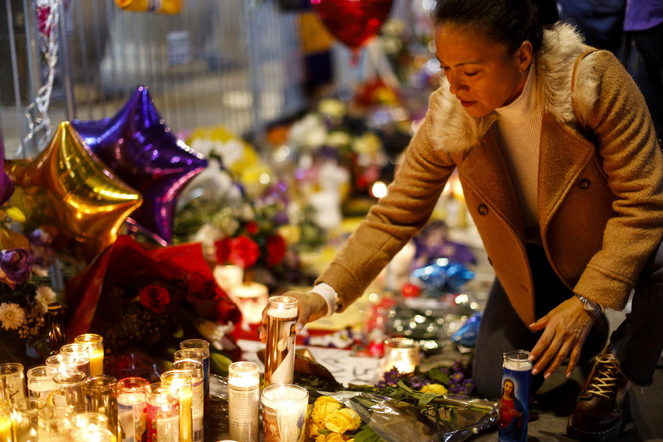 Angelica Diaz places a candle at a memorial for Kobe Bryant near Staples Center Tuesday, Jan. 28, 2020, in Los Angeles. Bryant, the 18-time NBA All-Star who won five championships and became one of the greatest basketball players of his generation during a 20-year career with the Los Angeles Lakers, died in a helicopter crash Sunday. (AP Photo/Ringo H.W. Chiu)