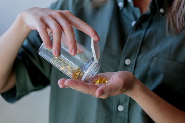 <p>Massonstock / Getty Images</p> An individual pours supplements from a clear jar