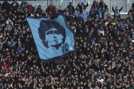 Napoli fans wave a flag portraying soccer legend Diego Armando Maradona during the Serie A soccer match between Napoli and Hellas Verona, at the Diego Armando Maradona stadium in Naples, Italy, Saturday, April 15, 2023. It's a celebration more than 30 years in the making, and historically superstitious Napoli fans are already painting the city blue in anticipation of the team's first Italian league title since the days when Diego Maradona played for the club. (Alessandro Garofalo/LaPresse via AP)