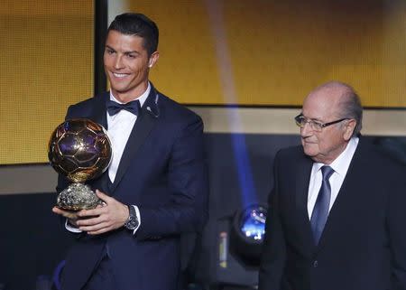 Real Madrid's Cristiano Ronaldo of Portugal, holds his World Player of the Year trophy as he stands next to FIFA President Sepp Blatter (R) during the FIFA Ballon d'Or 2014 soccer awards ceremony at the Kongresshaus in Zurich January 12, 2015. REUTERS/Ruben Sprich