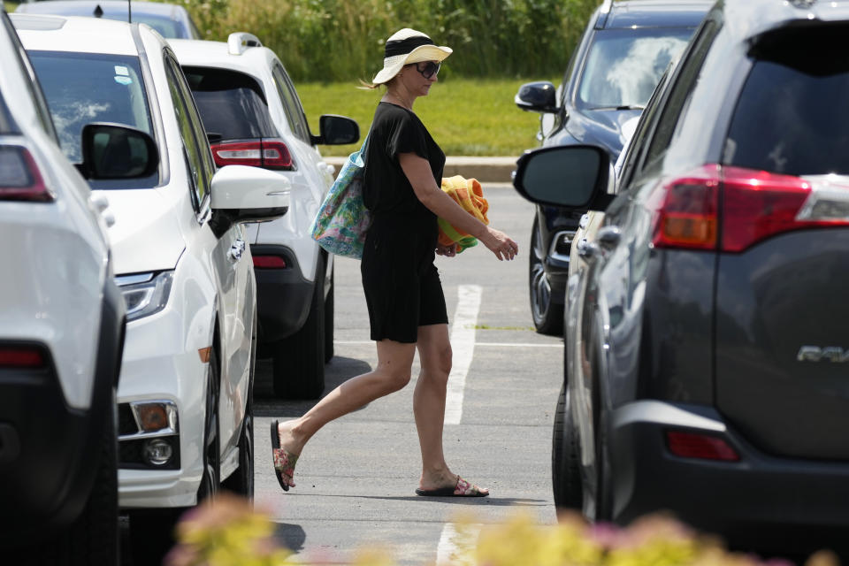 A woman walks in parking lot area at Heritage Park during hot weather in Riverwoods, Ill., Monday, June 17, 2024. (AP Photo/Nam Y. Huh)