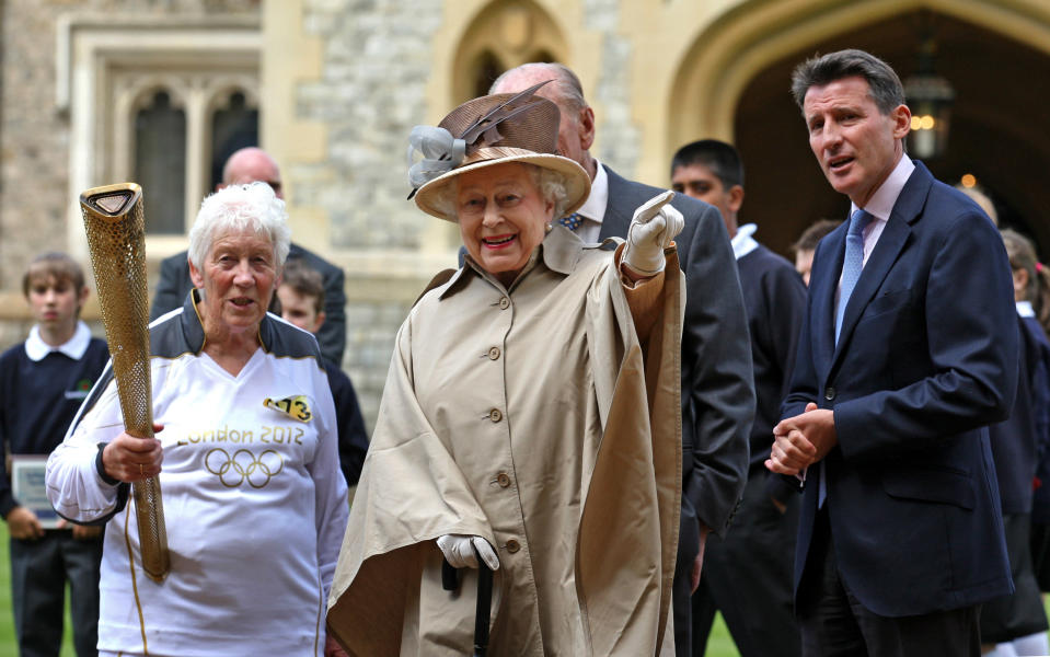 This image made available by LOCOG shows Queen Elizabeth II, center, and the Duke of Edinburgh, obscured, greeting Torchbearer 073 Gina Macgregor, left, and Olympic chairman Sebastian Coe right, outside Windsor Castle, Windsor, England Tuesday July 10, 2012. (AP Photo/Chris Radburn/LOCOG)