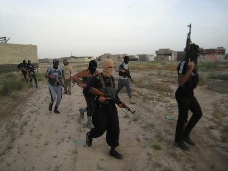 Masked Sunni gunmen walk with their weapons during a patrol outside the city of Falluja April 28, 2014. REUTERS/Stringer