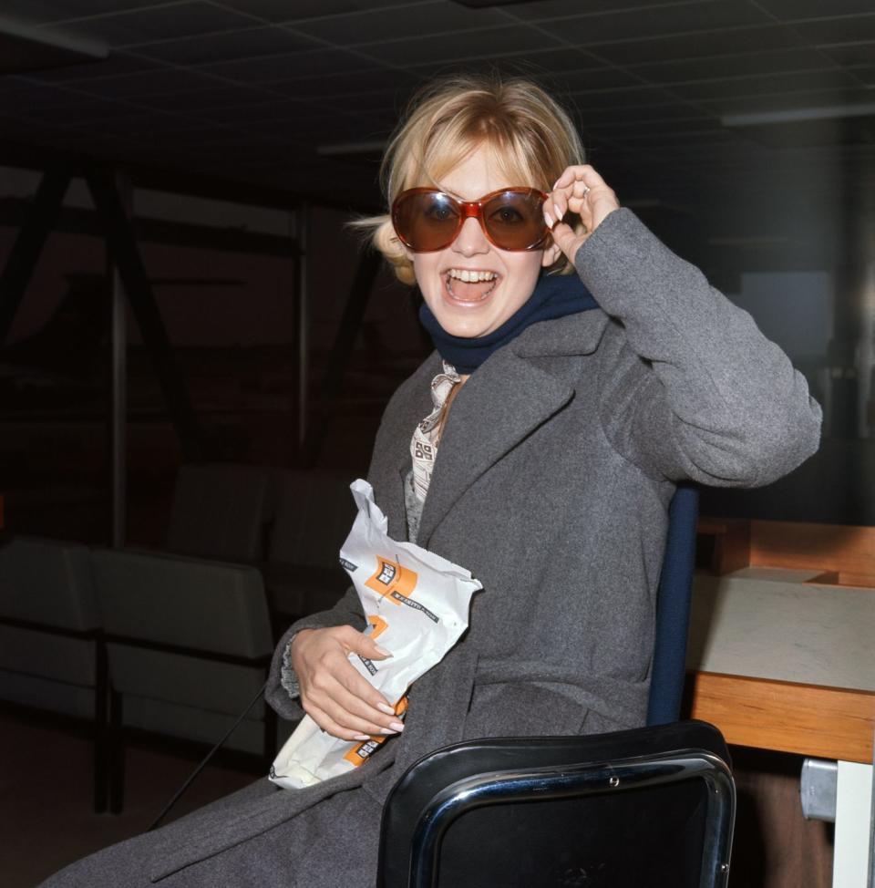 <p>Goldie Hawn waits for her plane to arrive, with a snack in hand, in 1970. </p>