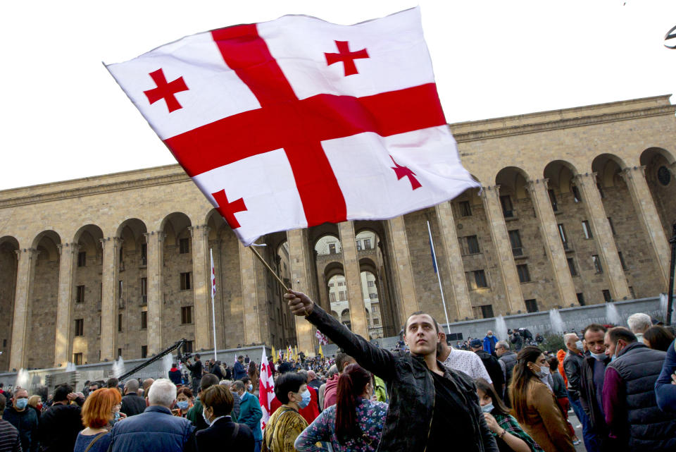 A supporter of the ex-President Mikhail Saakashvili's United National Movement, waves a Georgian national flag during a rally to protest the election results in front of the parliament's building in Tbilisi, Georgia, Sunday, Nov. 1, 2020. Preliminary election results show that Georgia's ruling party won the country's highly contested parliamentary election, but the opposition have refused to recognize Sunday's results. (AP Photo/Shakh Aivazov)