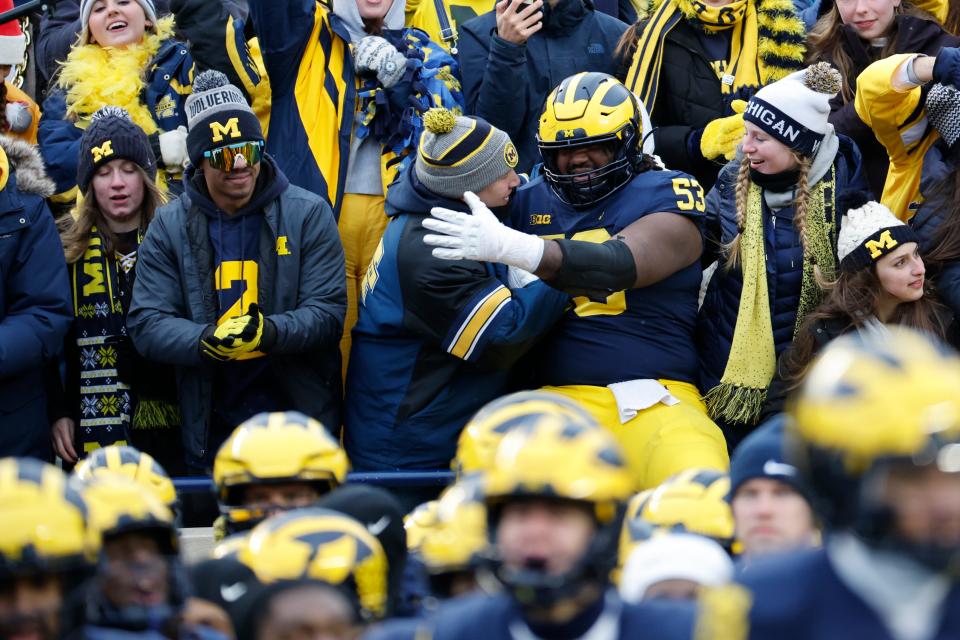 Michigan players celebrate with fans after a scare against Illinois on Saturday.