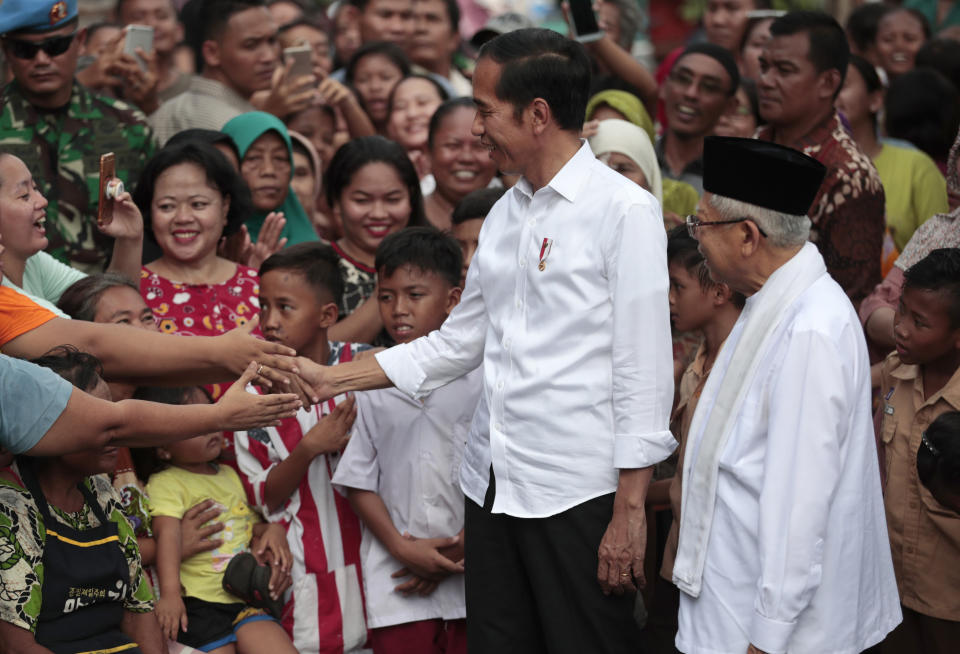 Indonesian President Joko Widodo, center, and his running mate Ma'ruf Amin are congratulated by residents after delivering their victory speech at a slum in Jakarta, Indonesia, Monday, Tuesday, May 21, 2019. Indonesia's President Joko Widodo has been elected for a second term, official results showed Tuesday, in a victory over a would-be strongman who aligned himself with Islamic hardliners. (AP Photo/Dita Alangkara)